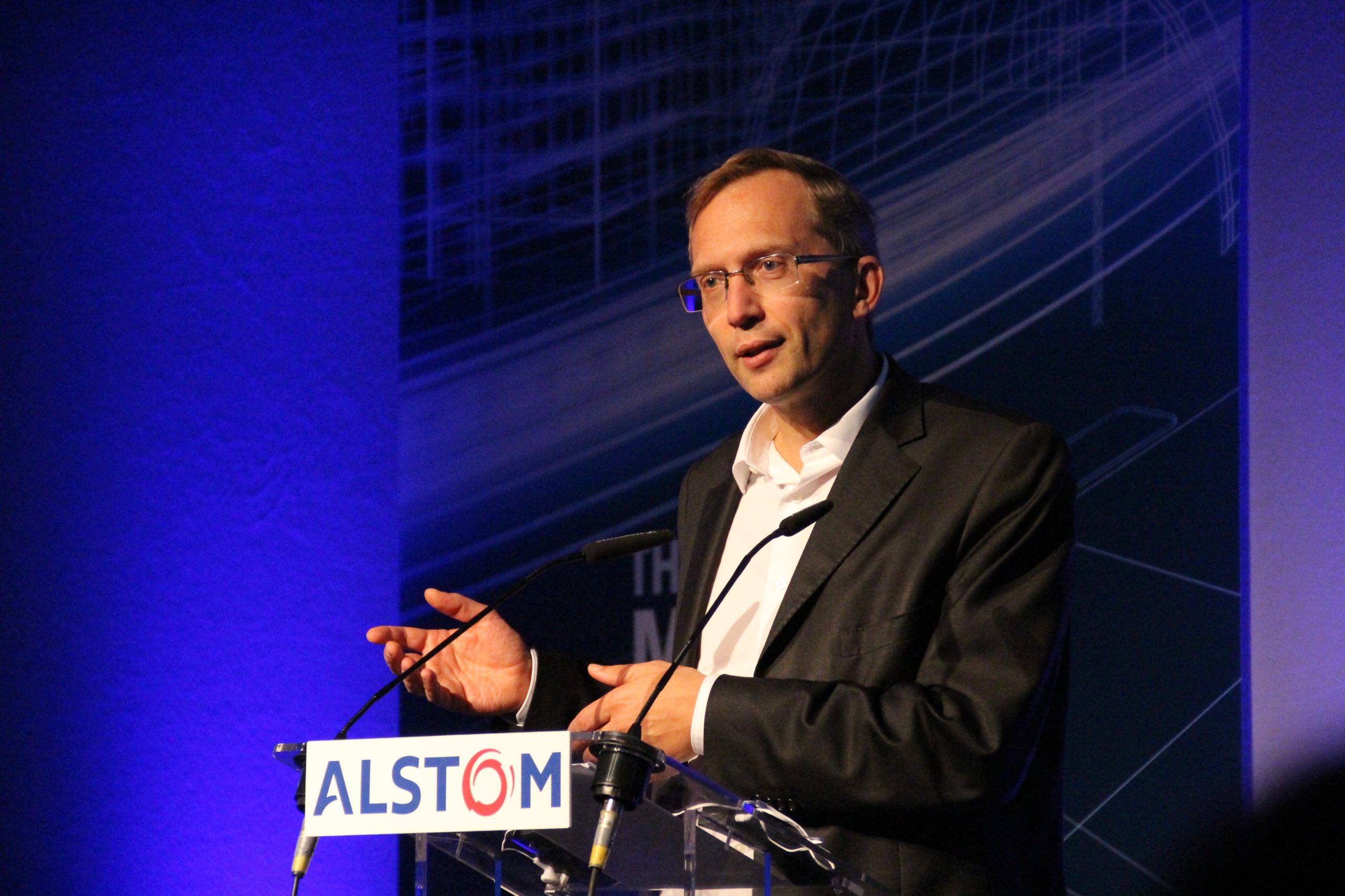 Man at podium with Alstom logo