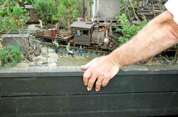 hand on benchwork next to model train