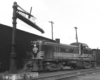 A black and white photo of a Diesel locomotive sitting on the tracks off to the side