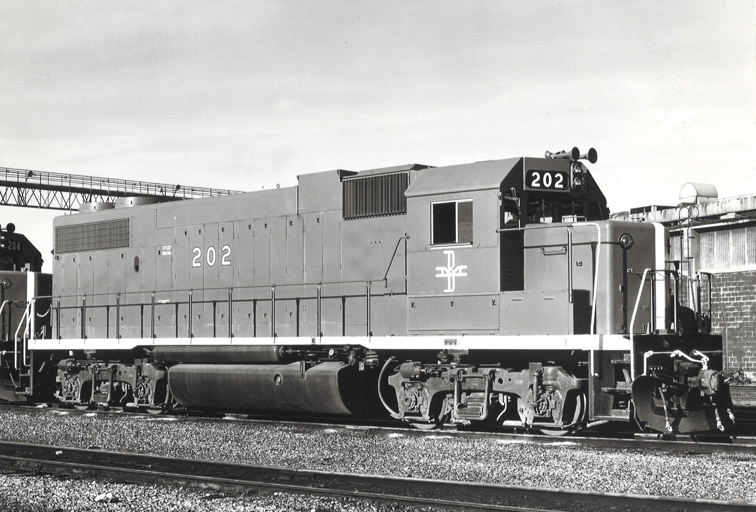 A black and white photo of a EMD locomotive sitting on the tracks