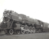 A close up black and white photo of a Mountain-type locomotive sitting on the tracks