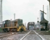 Green diesel switcher on diamond crossing by tower and bridges