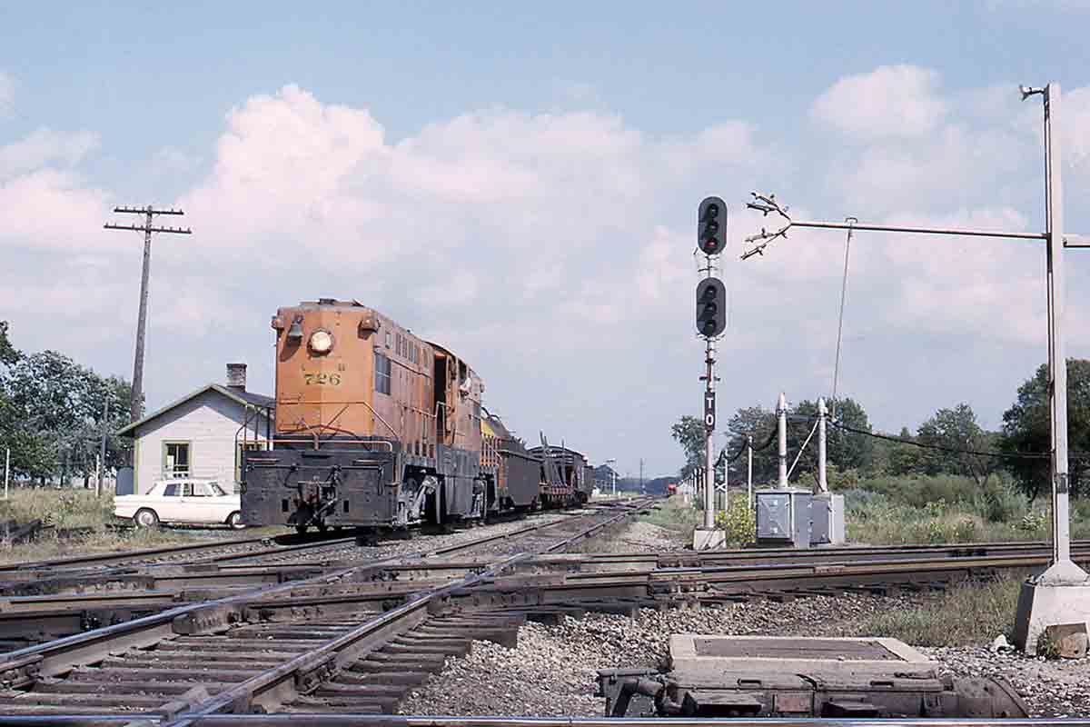 Orange center cab locomotive approaching diamond crossing