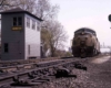 Black and gold diesel locomotive by tower and signal