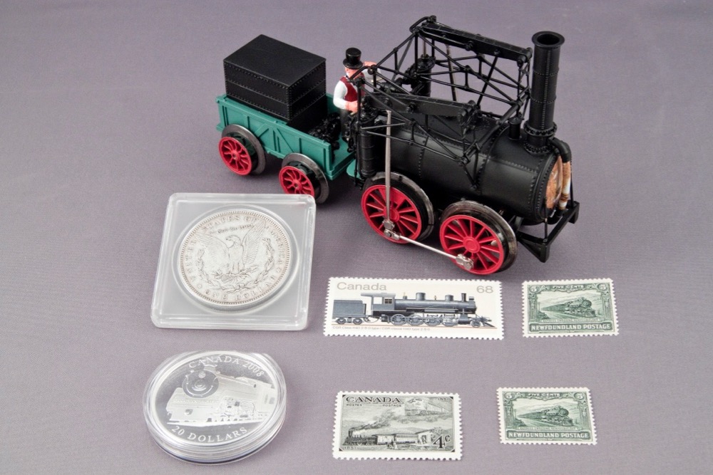 A model of an early looking toy train, an old U.S. silver dollar, a Canadian coin, and postage stamps from Canada.