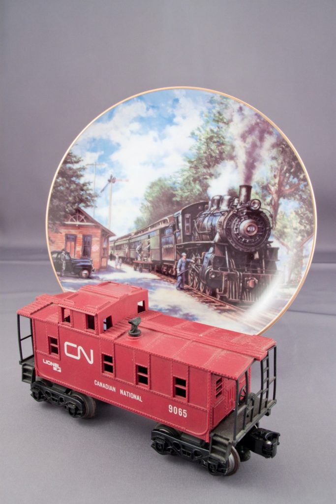 A collector's plate featuring a steam locomotive-hauled train and a Lionel-made Canadian National branded caboose.