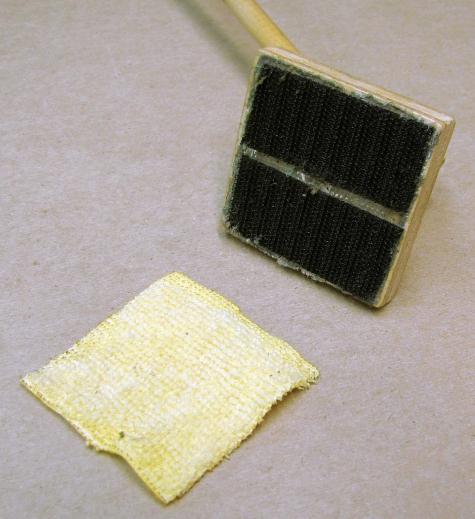 Showing the underside of the track cleaning tool with cleaning pad separate from velcro.