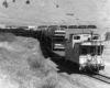 A black and white picture of a caboose transporting vehicles