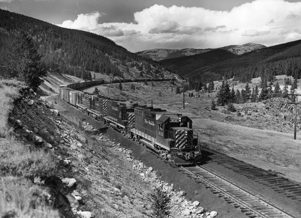 A black and white photo of a diesel locomotive turning a corner on the track