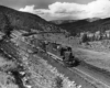 A black and white photo of a diesel locomotive turning a corner on the track