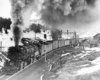 A black and white photo of a 2-8-8-2 steam locomotive turning the corner on the tracks with a lot of smoke coming out of its chimney