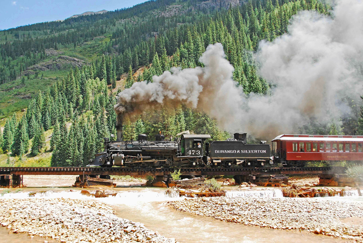 Steam locomotive pulling train across bridge