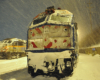 A closeup shot of a train parked, covered in snow.