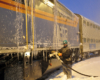 A worker filling a snowy and icy train with fuel