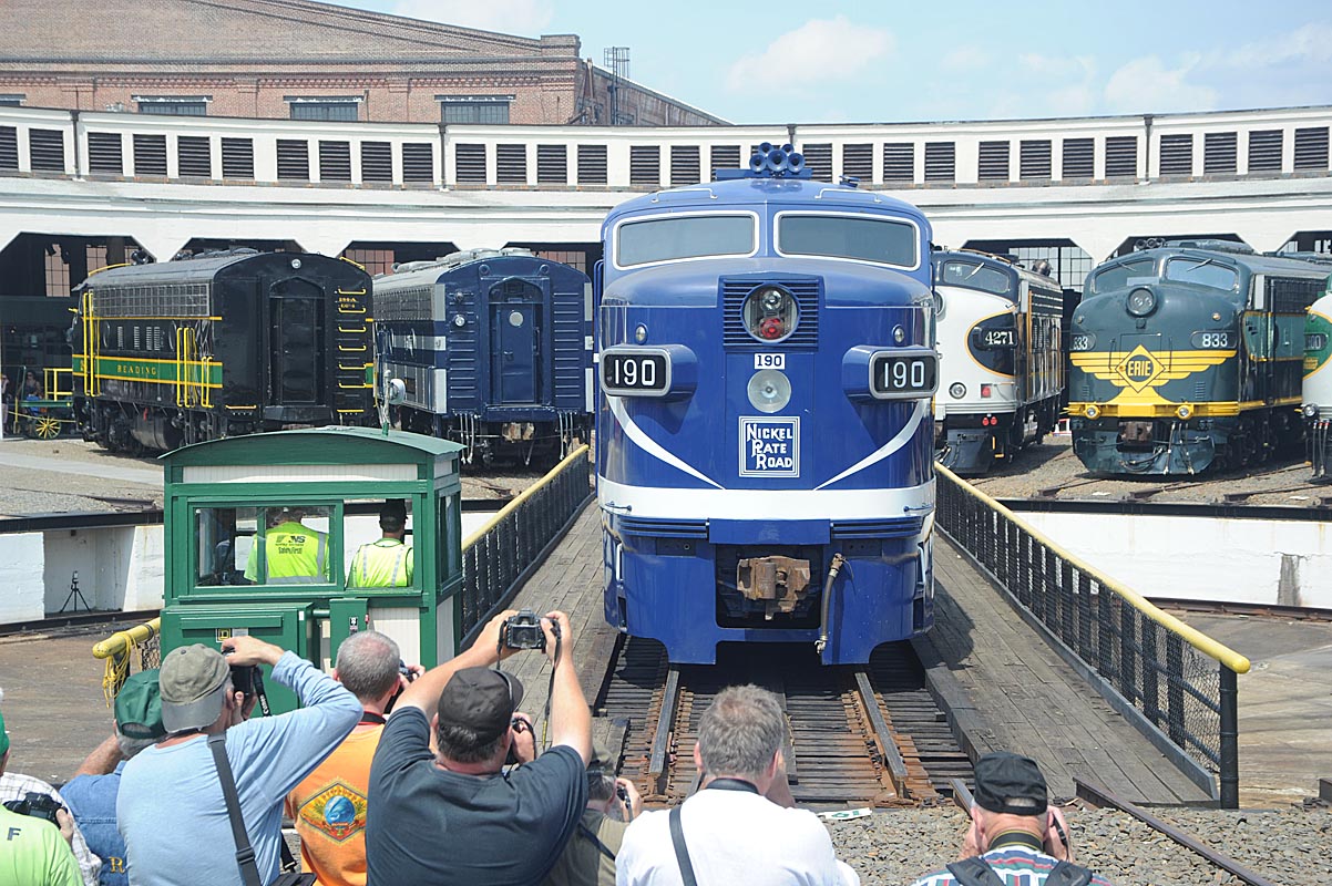 People taking pictures of a train on a turntable