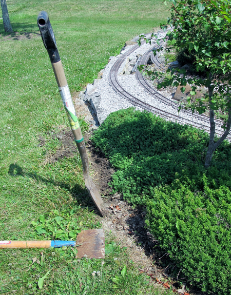 shovel and ice scraper near corner of garden railway