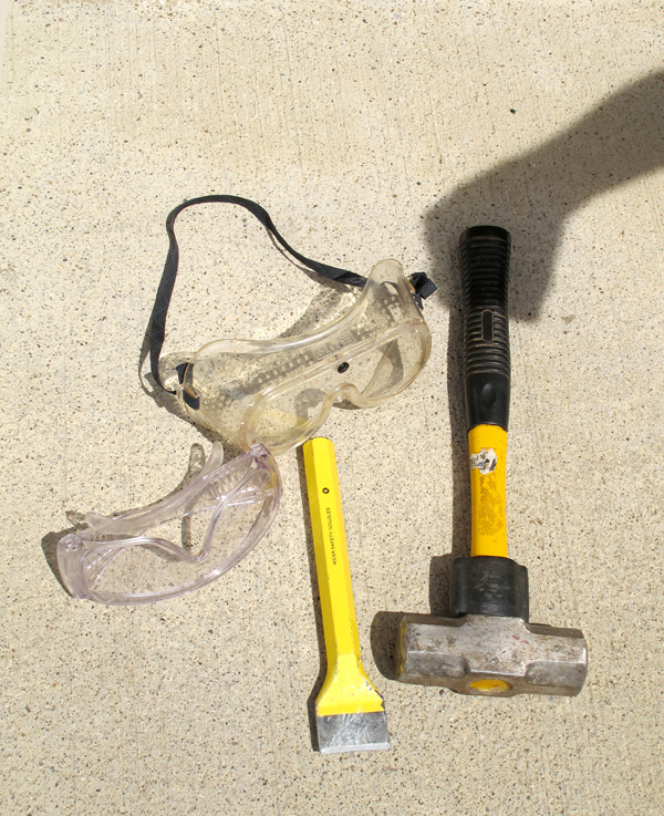 four tools on concrete with shadow hand pretending to grip one of the tools