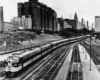 a diesel passenger train in front of buildings