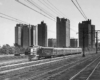 a diesel passenger train in front of some buildings