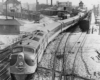 a diesel passenger train with buildings in the background