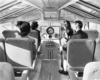 A black and white photo of people sitting inside a train