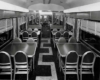 A black and white photo of the inside of an empty lounge diner train