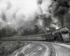 A black and white photo of a train turning a corner