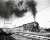 A black and white photo of a train with big black smoke coming out of it