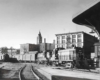 a diesel passenger train in front of buildings