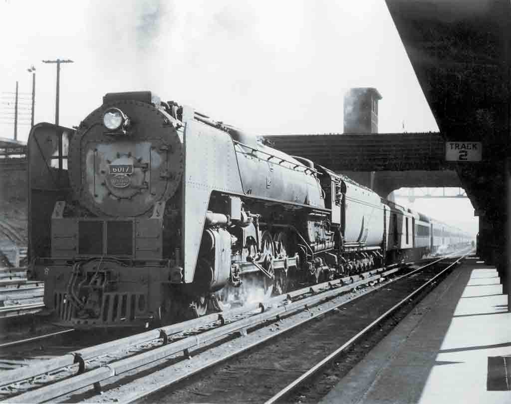 a steam locomotive passenger train at a depot