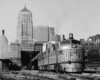 a diesel passenger train witih a train station in the background