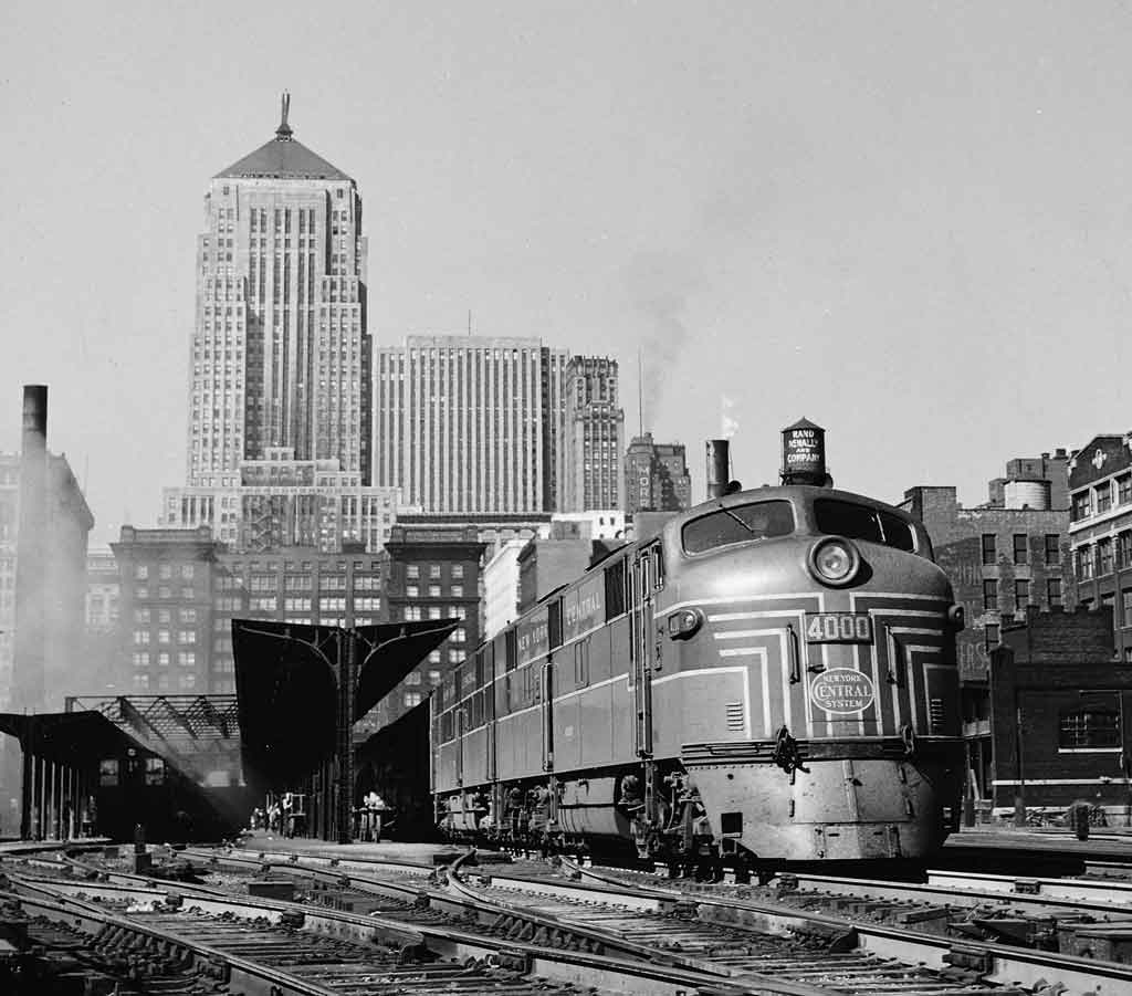 a diesel passenger train witih a train station in the background