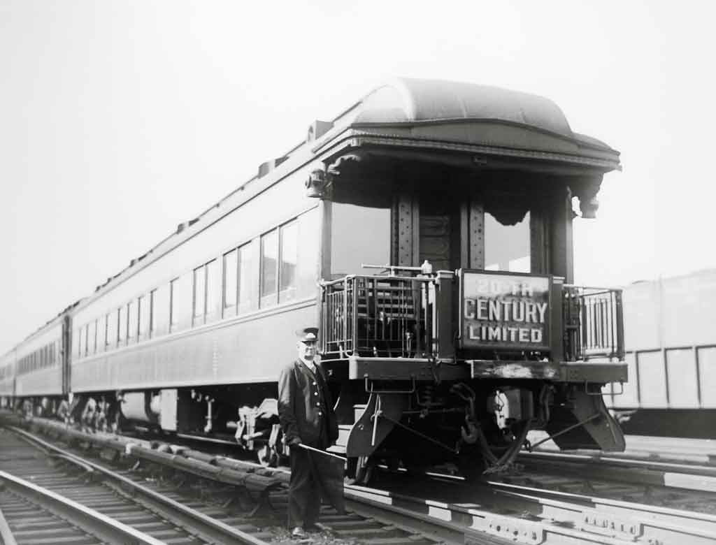 a conductor standing in front of an observation car