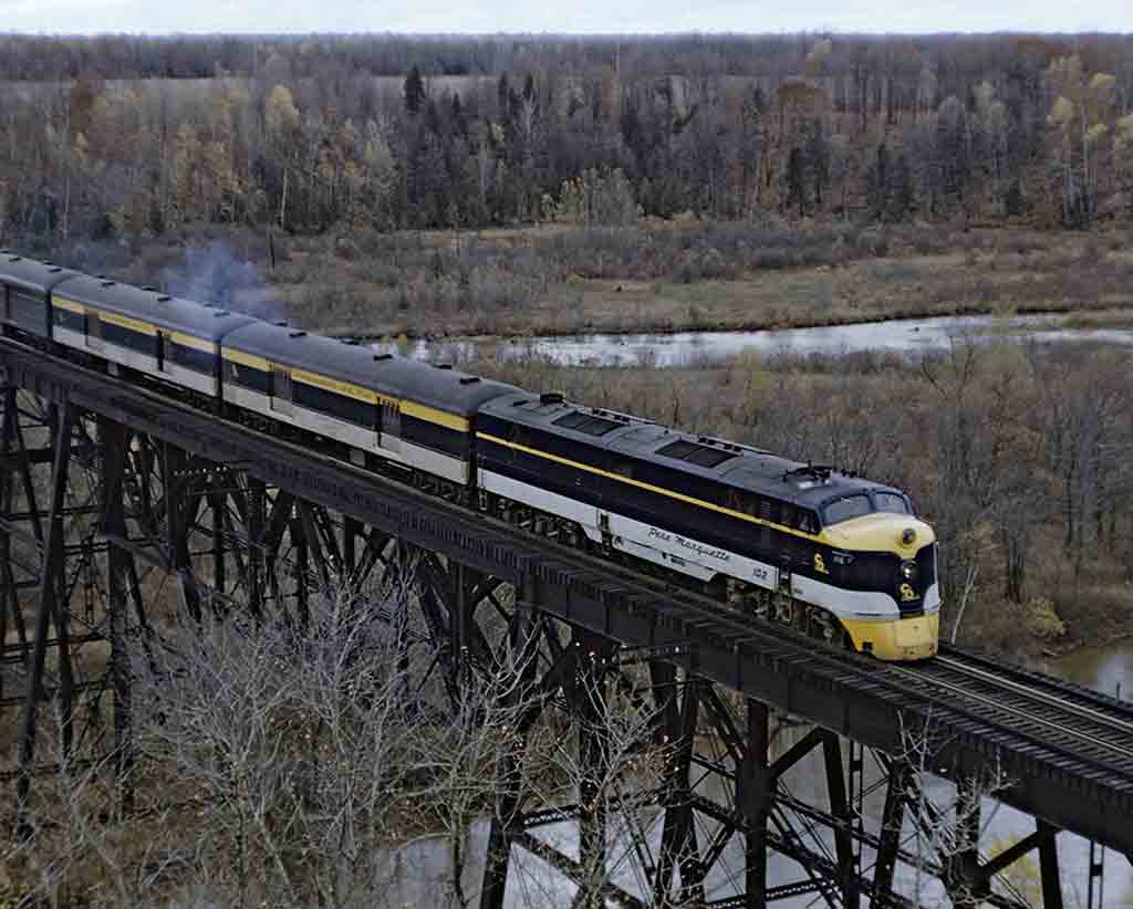 a diesel passenger train crossing a tall bridgea bridge
