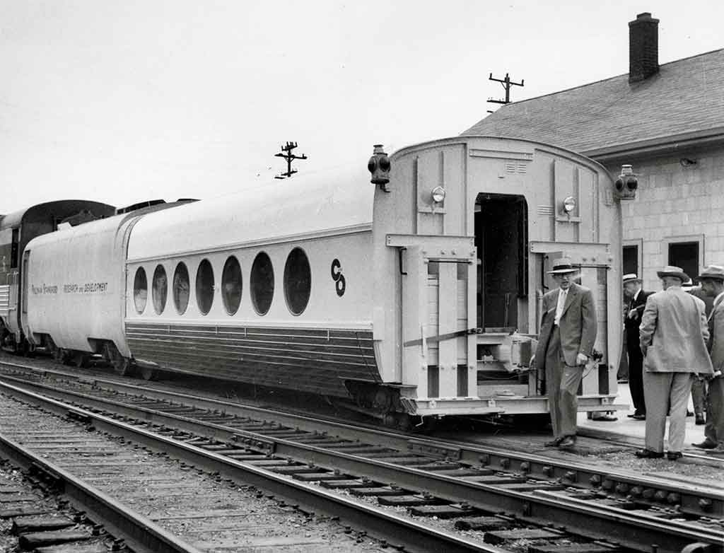 a group of people inspecting a passenger car with circular windows