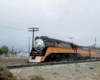 A black locomotive with an orange and red stripe coming down the tracks