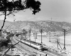 A black and white photo of a locomotive turning a corner with mountains in the background