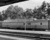 A close up black and white photo of a dome lounge car sitting on the tracks