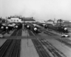 A black and white distant photo of locomotives sitting in a rail yard