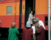 Passengers boarding an orange and red locomotive