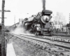 A black and white photo of a train leaving a station