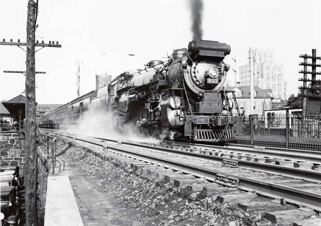 A black and white photo of a train leaving a station