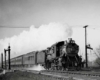 A black and white photo of a train with white smoke coming out of its chimney