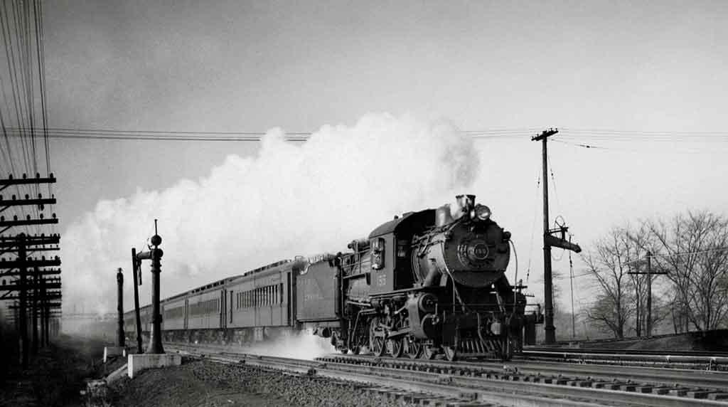 A black and white photo of a train with white smoke coming out of its chimney