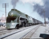 A green locomotive coming down the tracks with black smoke coming out of its chimney