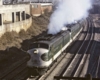 A green and white locomotive leaving a train station