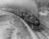 A black and white photo of a train turning a corner