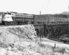 Diesel locomotive on steel bridge with four passenger cars