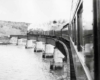 Steam powered passenger train on curved bridge over water