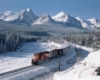Diesel locomotives in snow amid forests and mountains